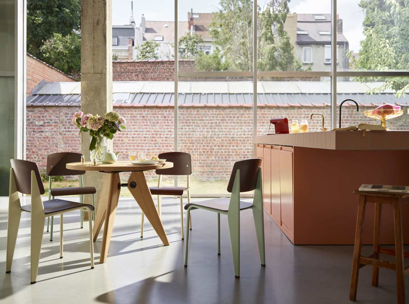 Vitra Guéridon Tisch mit Holzgestell und runder Tischplatte, umgeben von Stühlen in modernem Ambiente.