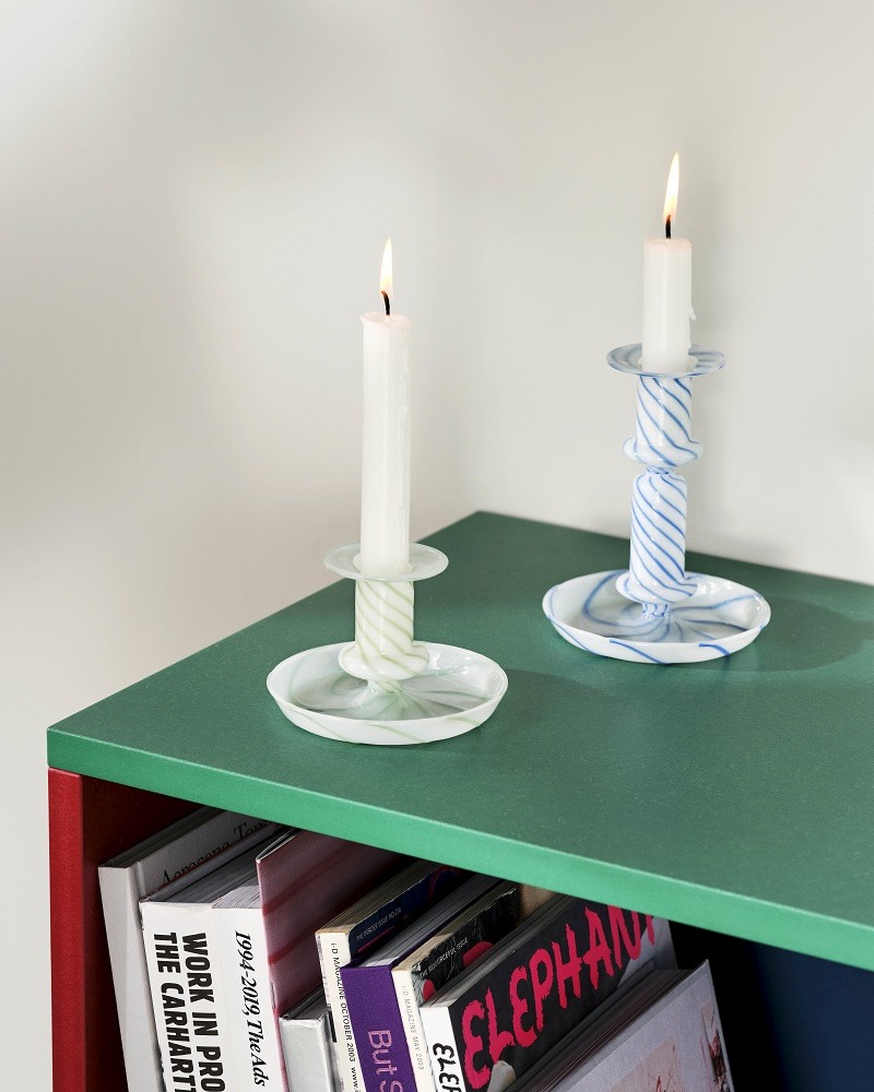 Colour Cabinet Sideboard: Zwei Kerzenleuchter aus Glas auf grüner Oberfläche mit Büchern.