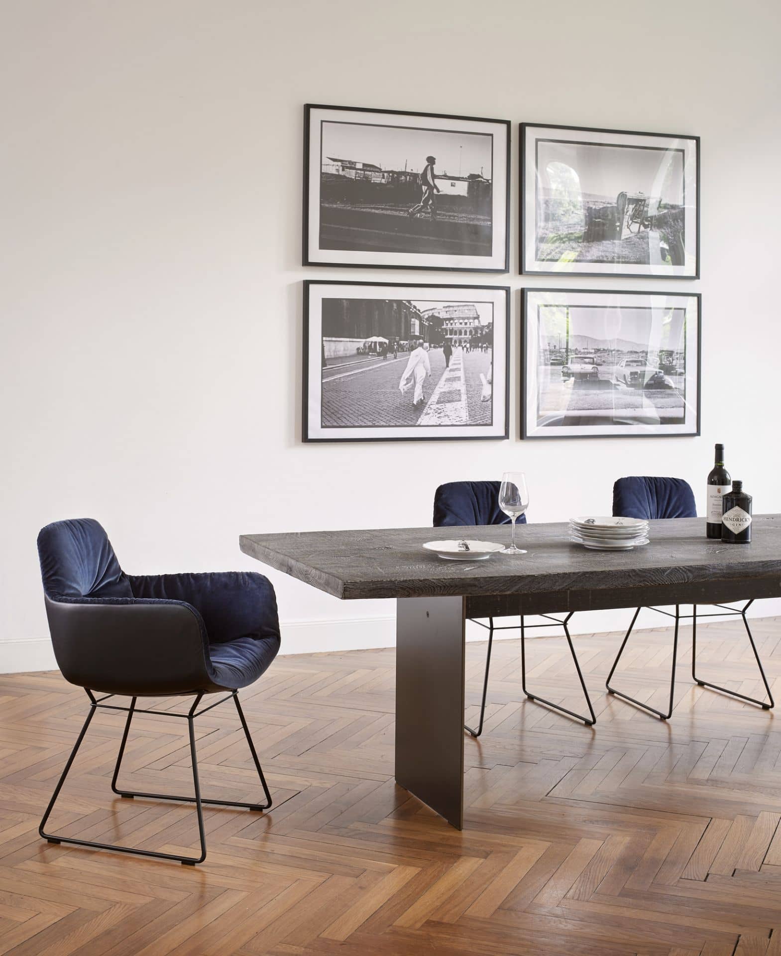 Esstisch aus dunklem Holz mit blauen Samtstühlen und schwarzen Metallbeinen im modernen Esszimmer.