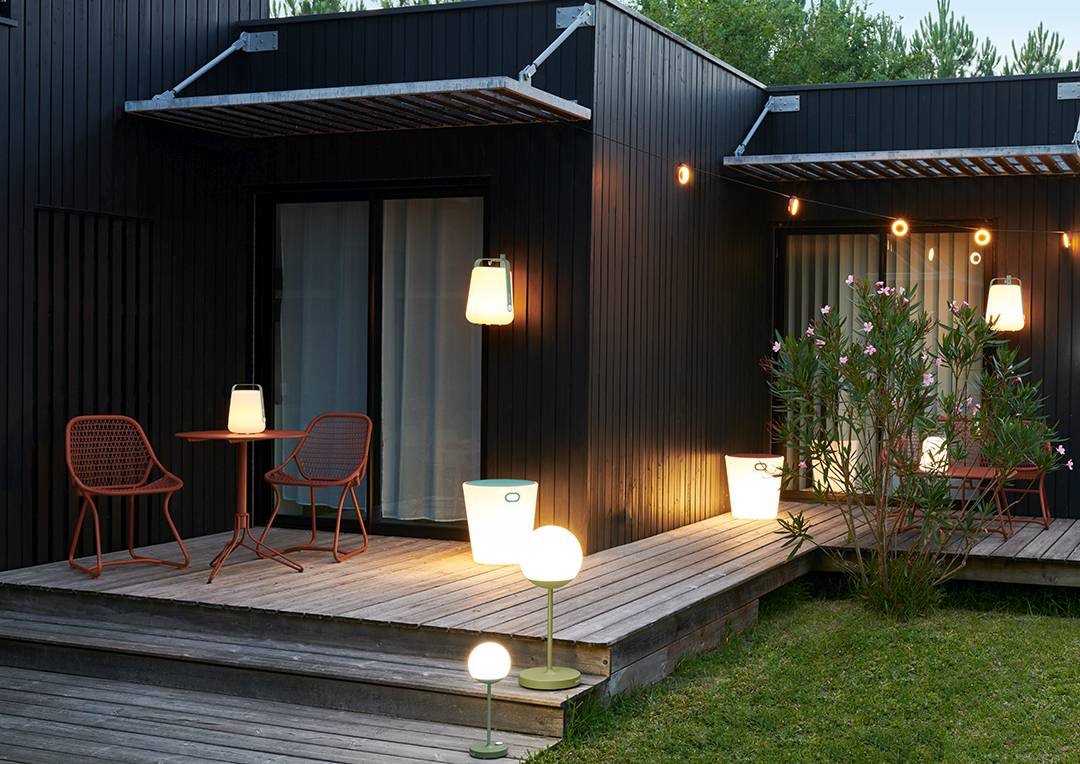 Außenbereich mit Sixties Stühlen von Fermob, Tisch und verschiedenen Leuchten auf einer Holzterrasse.