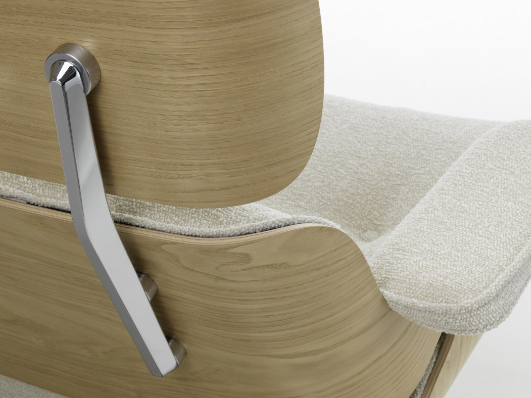 Detailaufnahme Eames Lounge Chair Sessel: Helles Holzfurnier, cremefarbene Polsterung und verchromter Armlehnen-Halter für luxuriösen Komfort.