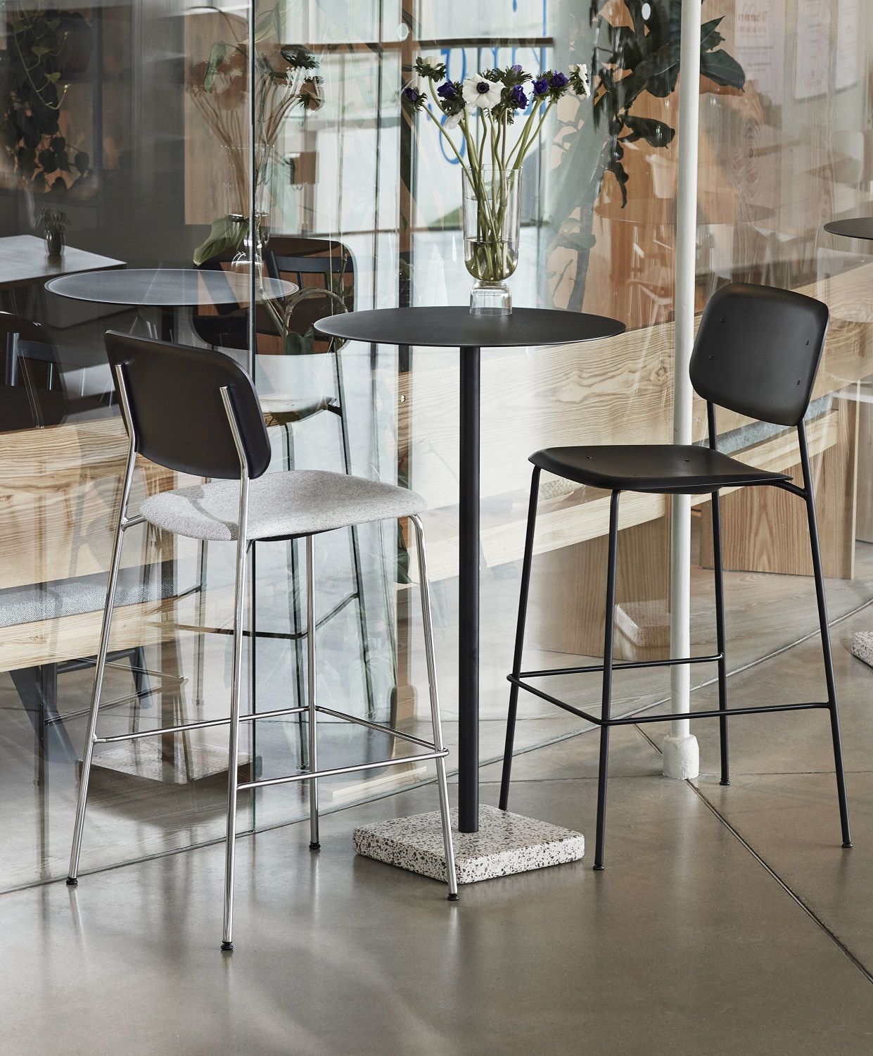 Zwei Hay Soft Edge Barhocker (Low/High) in Schwarz und Grau an einem Bistrotisch.