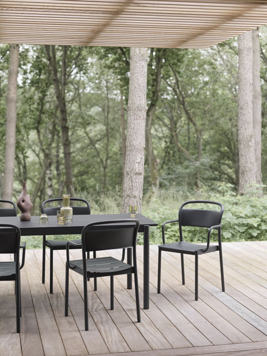 Muuto Linear Steel Table Outdoor Tisch mit Stühlen auf einer Holzterrasse vor Wald.