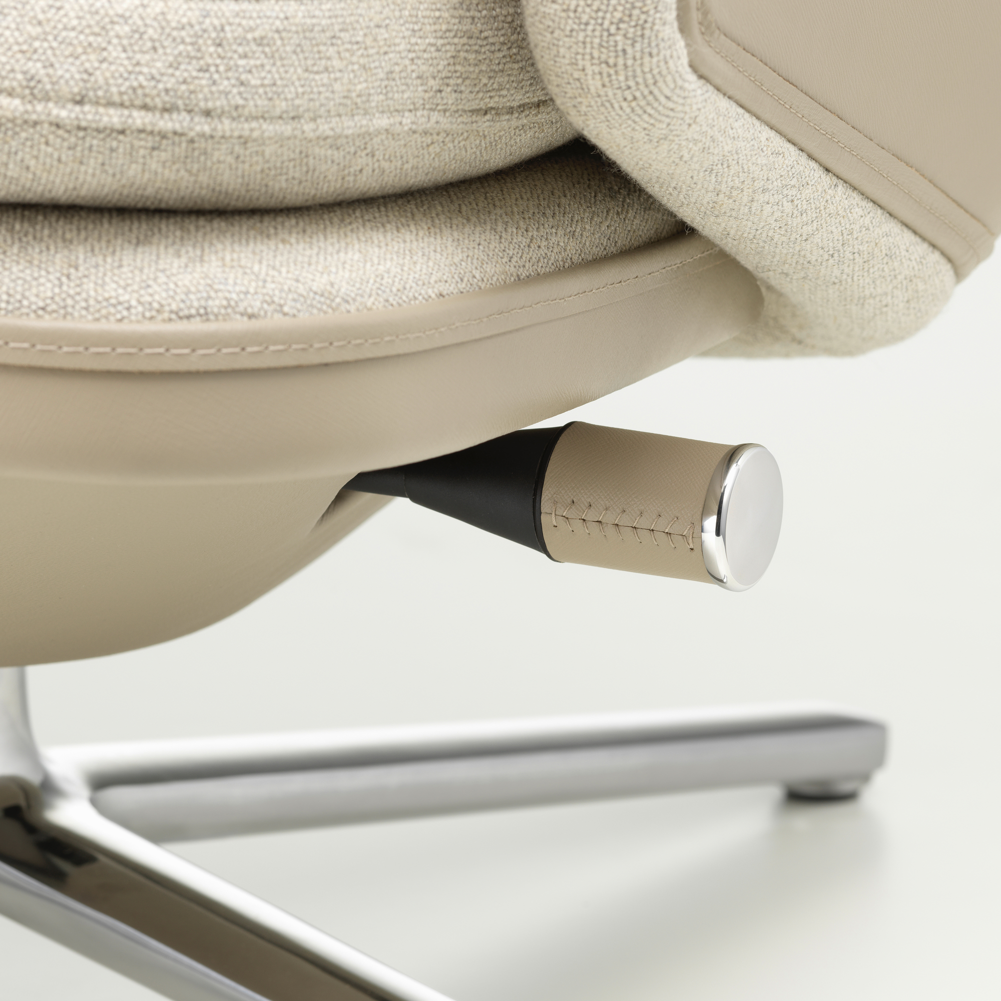 Detailaufnahme des Grand Relax Sessels von Vitra: Verstellmechanismus, beiger Stoffbezug und Chromfußkreuz.