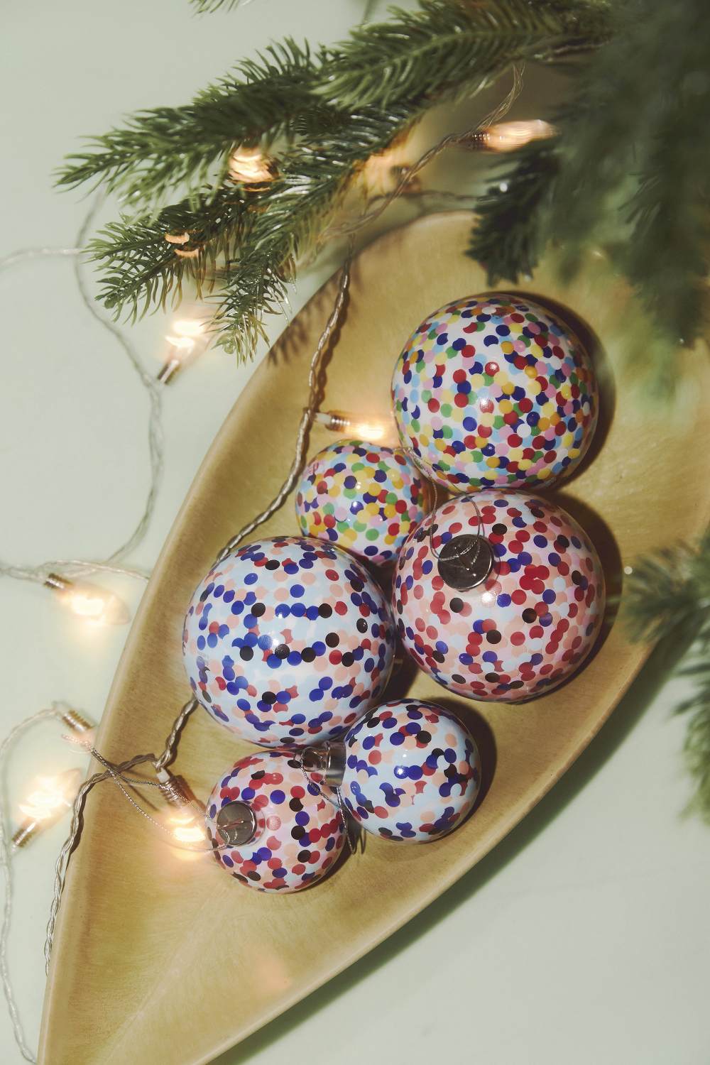 Alessi Proust Kugel: Weihnachtskugeln mit bunten Punkten in einer Holzschale mit Lichterkette.