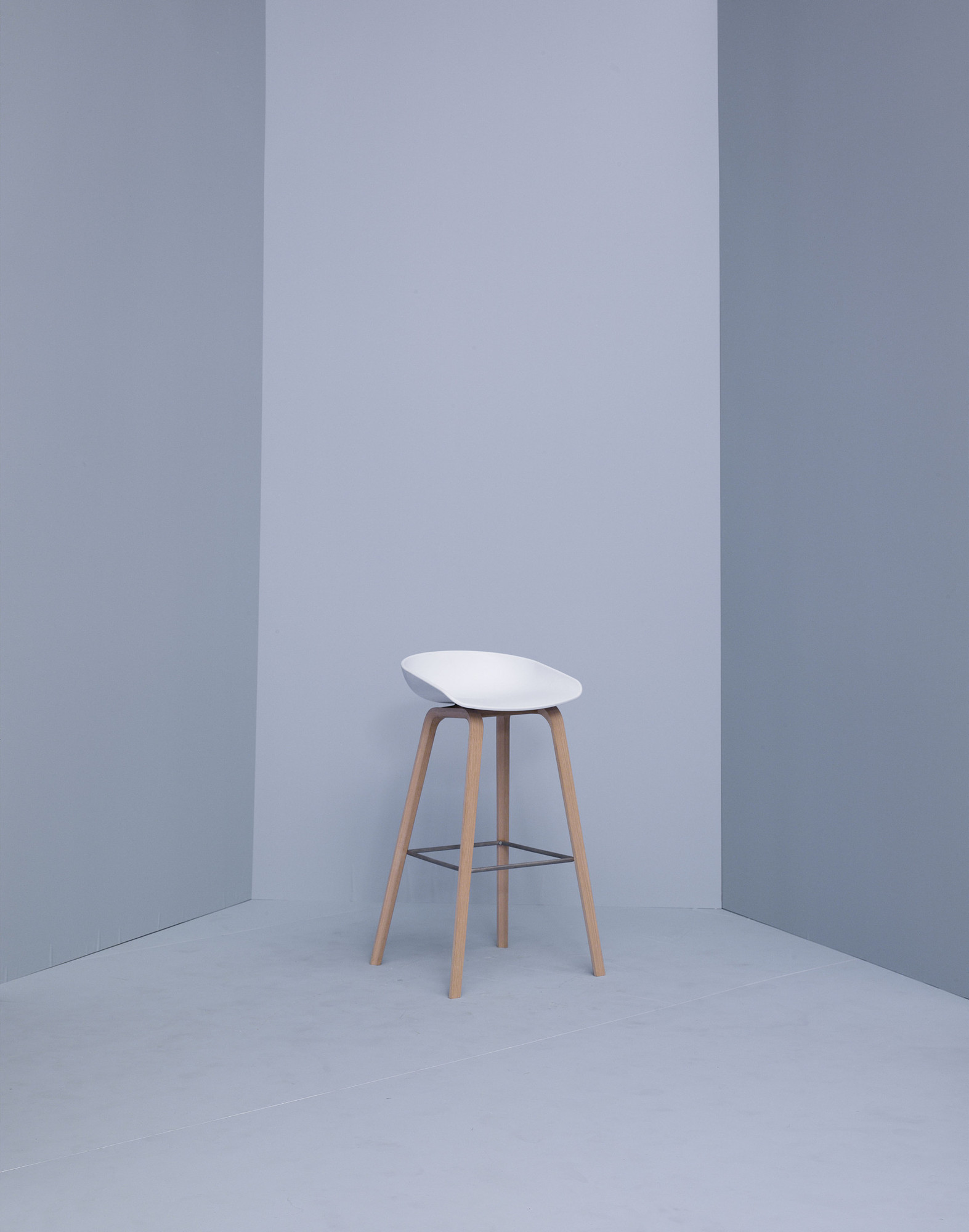 Weißer Hay About a Stool AAS32 Barhocker mit Holzbeinen vor grauem Hintergrund. Moderner skandinavischer Barstuhl.