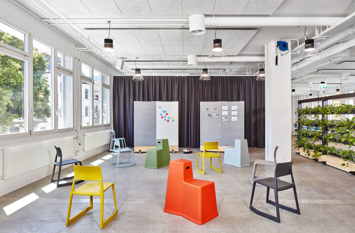 Büroraum mit mehreren farbigen Tip Ton Stühlen aus Kunststoff von Vitra, ergonomische Sitzmöbel.
