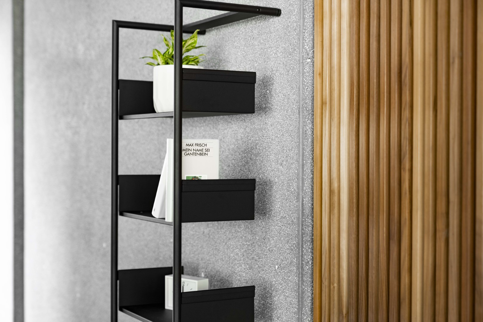 Schwarzes Pool 196 Medium Anlehnregal von Mox mit Pflanze, Buch und Dekoration vor Wand.