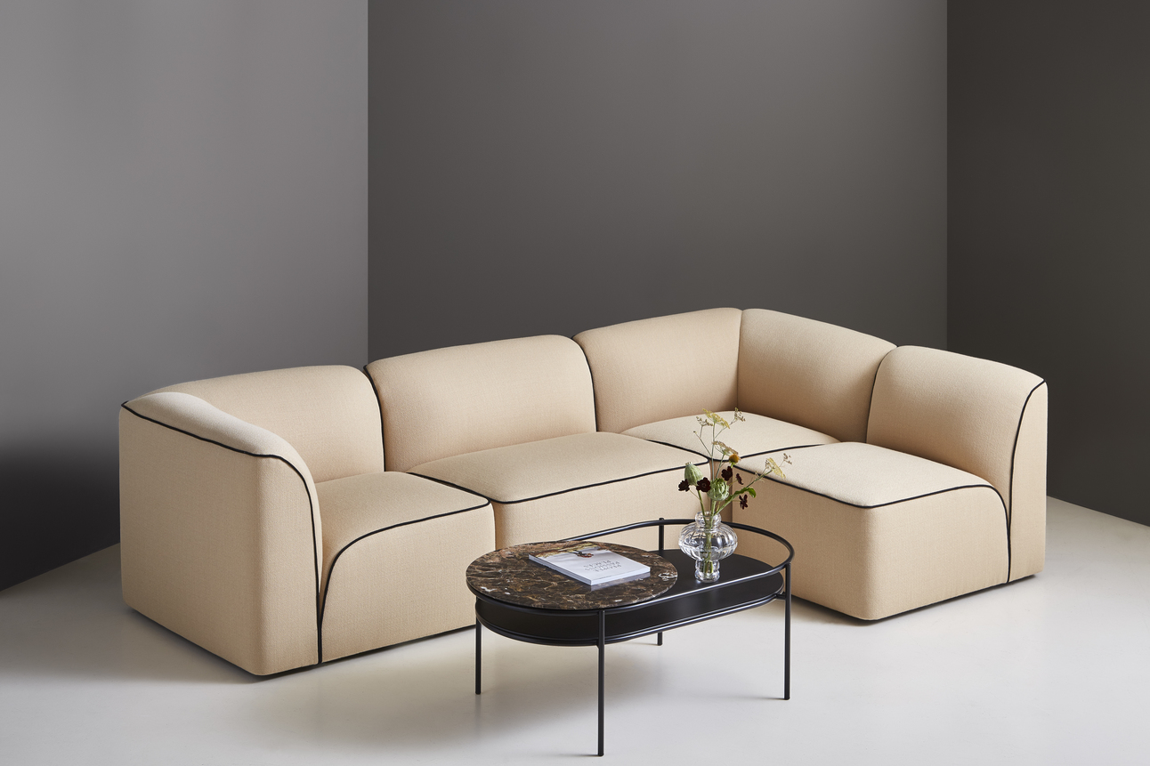 Beige Flora Modul-Sofa mit schwarzer Paspelierung und passendem Couchtisch im modernen Wohnzimmer.