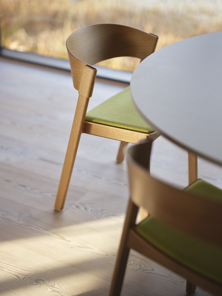 Detailaufnahme des Muuto MIDST Table Esstischs mit Holzstühlen und grünen Sitzpolstern in modernem Design.