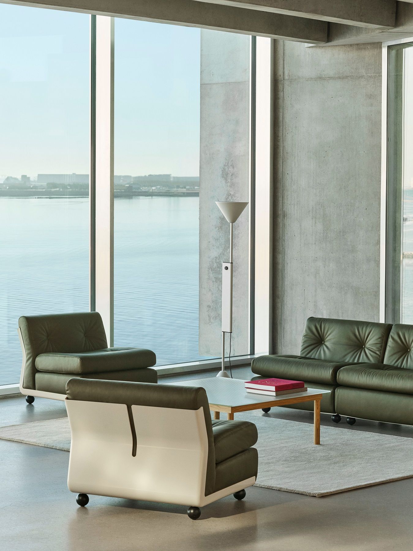 Helle, moderne Wohnung mit Hay Twist Floor Lamp Stehleuchte, grünen Ledersofas und Meerblick.
