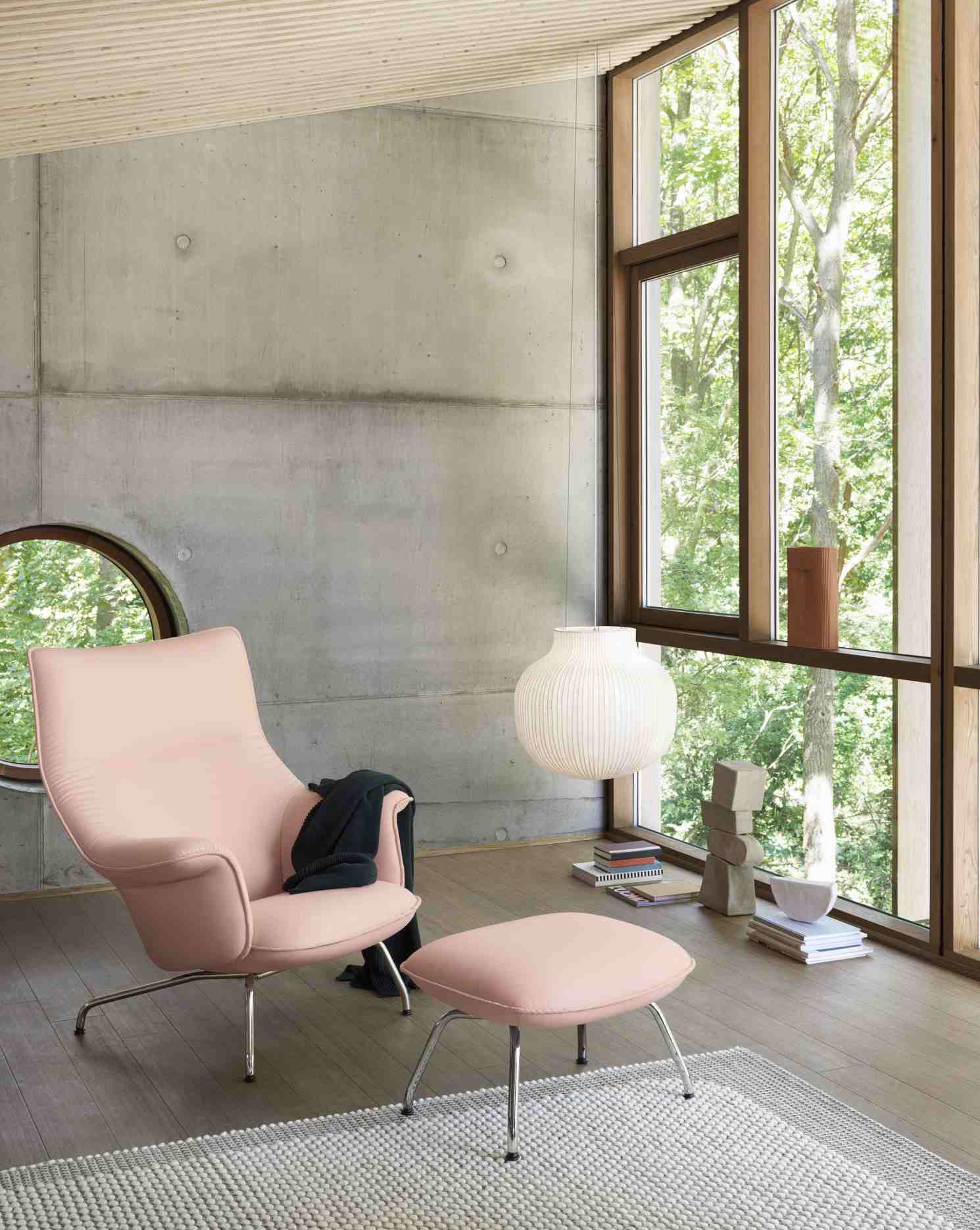 Helle Muuto Strand Pendelleuchte über Sessel und Hocker in modernem Wohnzimmer mit großem Fenster.