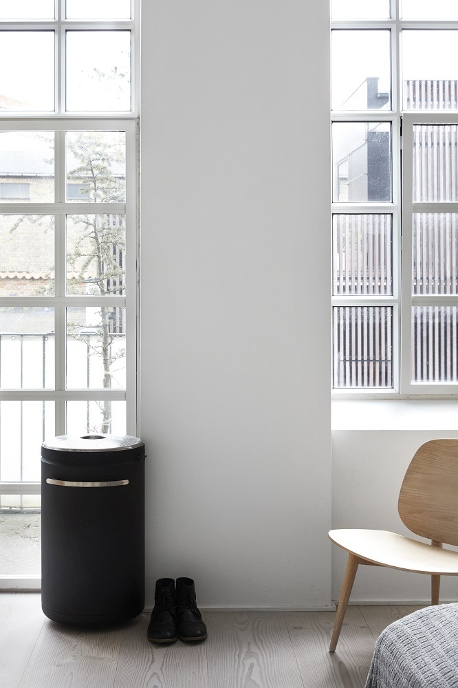 Schwarzer Vipp Wäschekorb aus Stahl im minimalistischen Schlafzimmer mit Holzfußboden und Tageslicht.