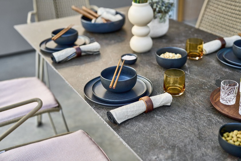 Slope Tisch von Weishäupl, gedeckt mit Geschirr, Gläsern und Servietten für ein asiatisches Outdoor-Dinner.
