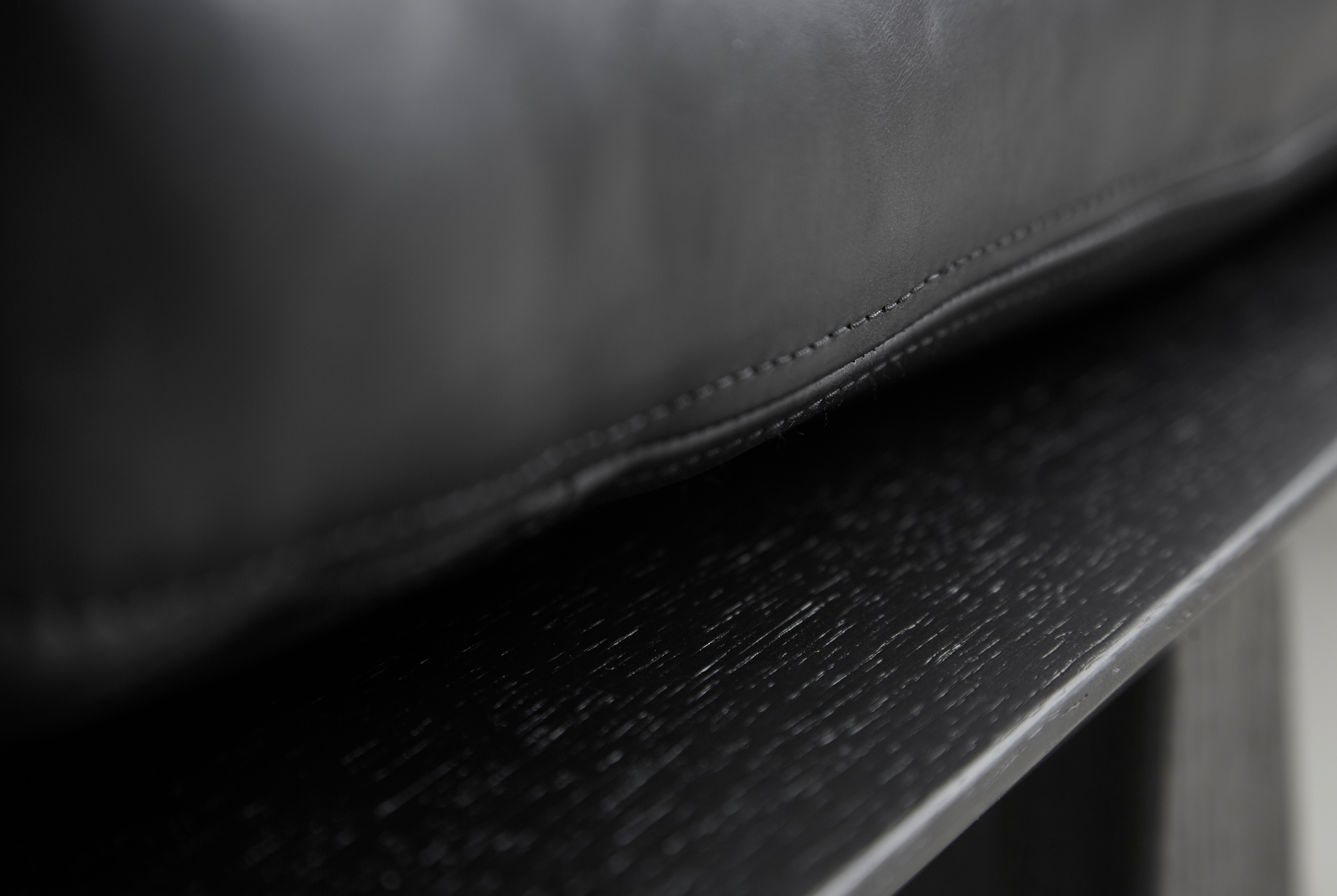 Detailaufnahme: Schwarze Level Daybed Liege von Woud mit Lederpolsterung und Holzrahmen.