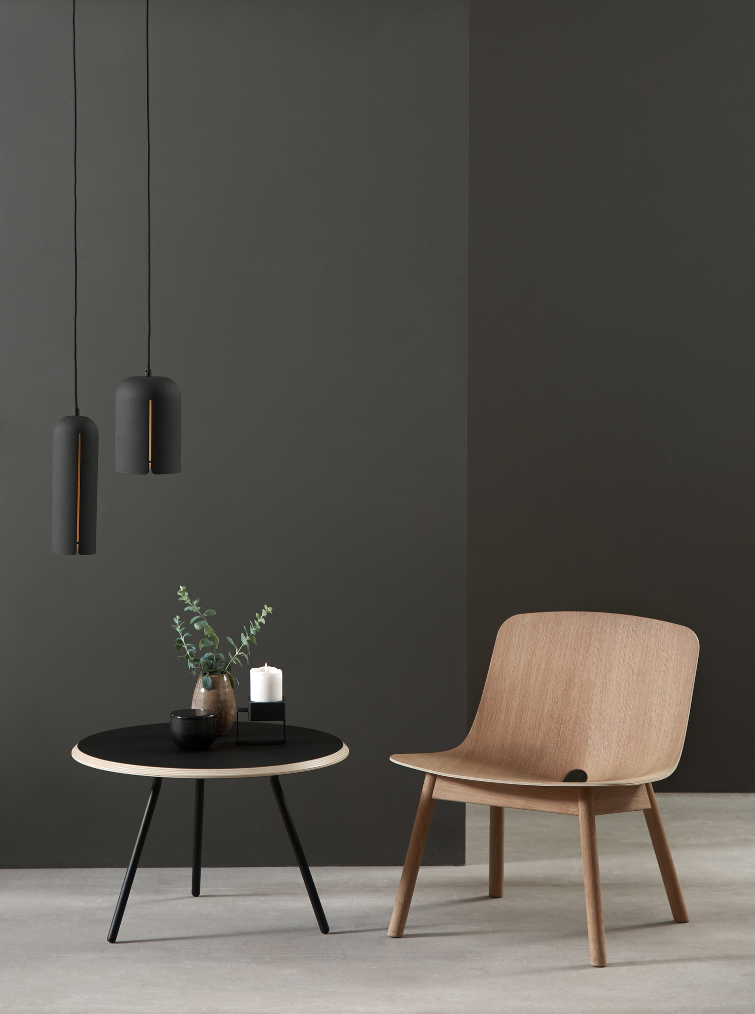 Beiger Soround Coffee Table Couchtisch von Woud mit Dekoration und Holzstuhl vor dunklem Hintergrund.