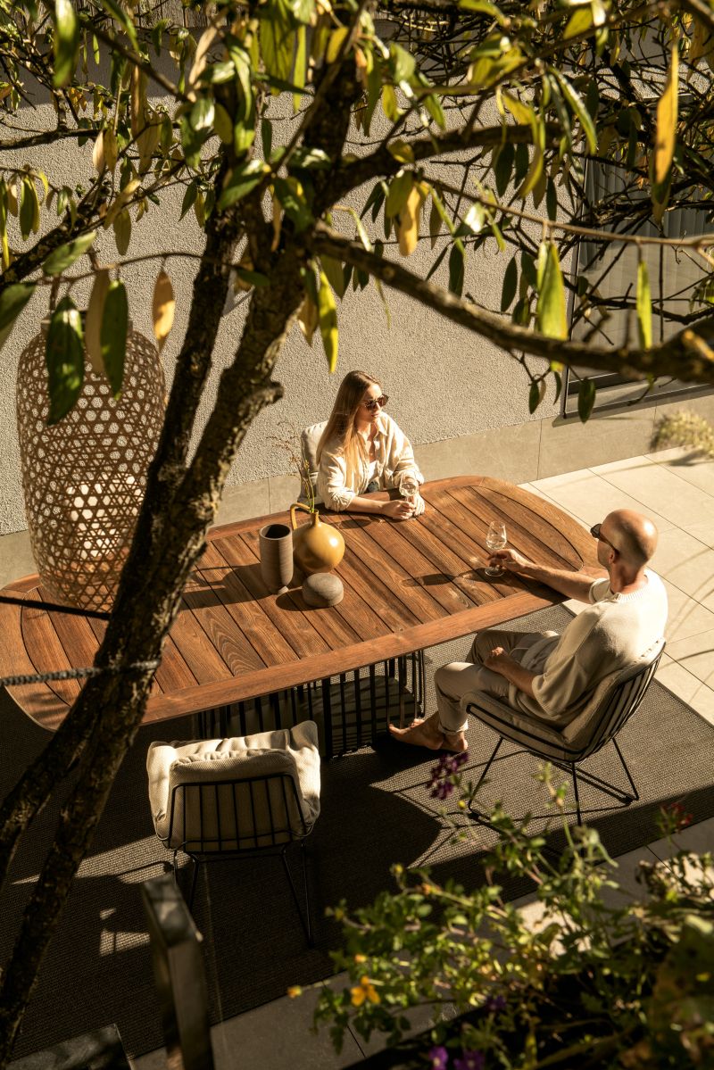 BC 07 Basket Outdoor Tisch von Janua, bootsförmig, mit Personen im Garten.