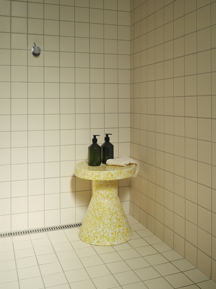 Gelber Bit Stool Cone Hocker von Normann Copenhagen im Badezimmer mit Seifenspendern und Handtuch.
