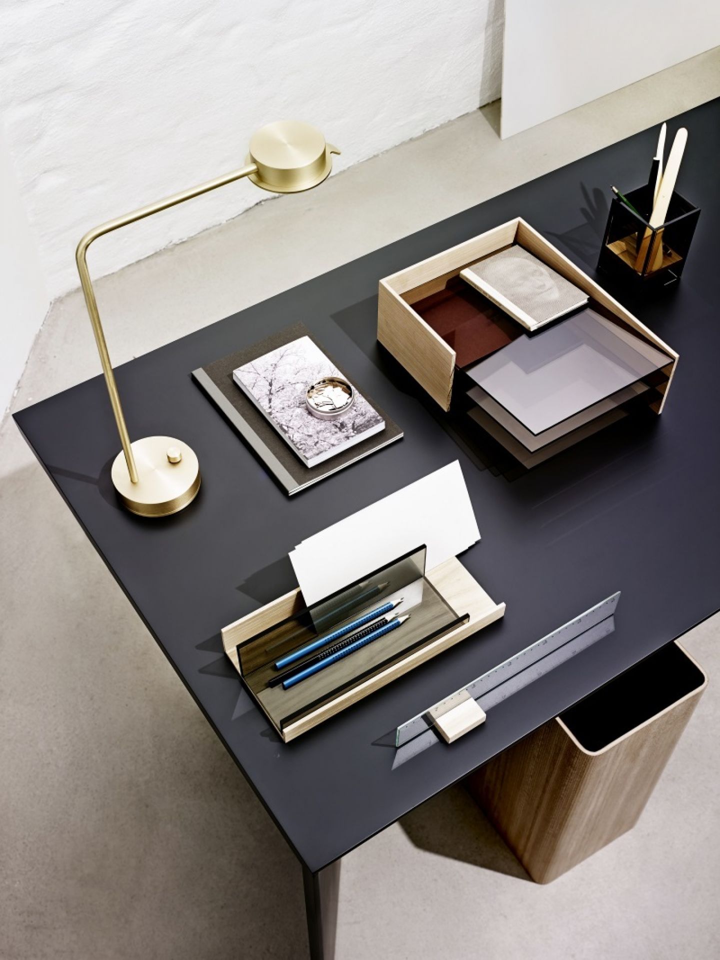 Schreibtisch mit goldener Lampe, Holzablage, Stifthalter, Notizbüchern, Stiften und Lineal für Büroorganisation und stilvolles Arbeiten.