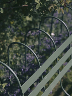 Detailaufnahme des Gardener's Sofa Outdoor von Design House Stockholm, grüne Metallstruktur vor blühendem Garten.