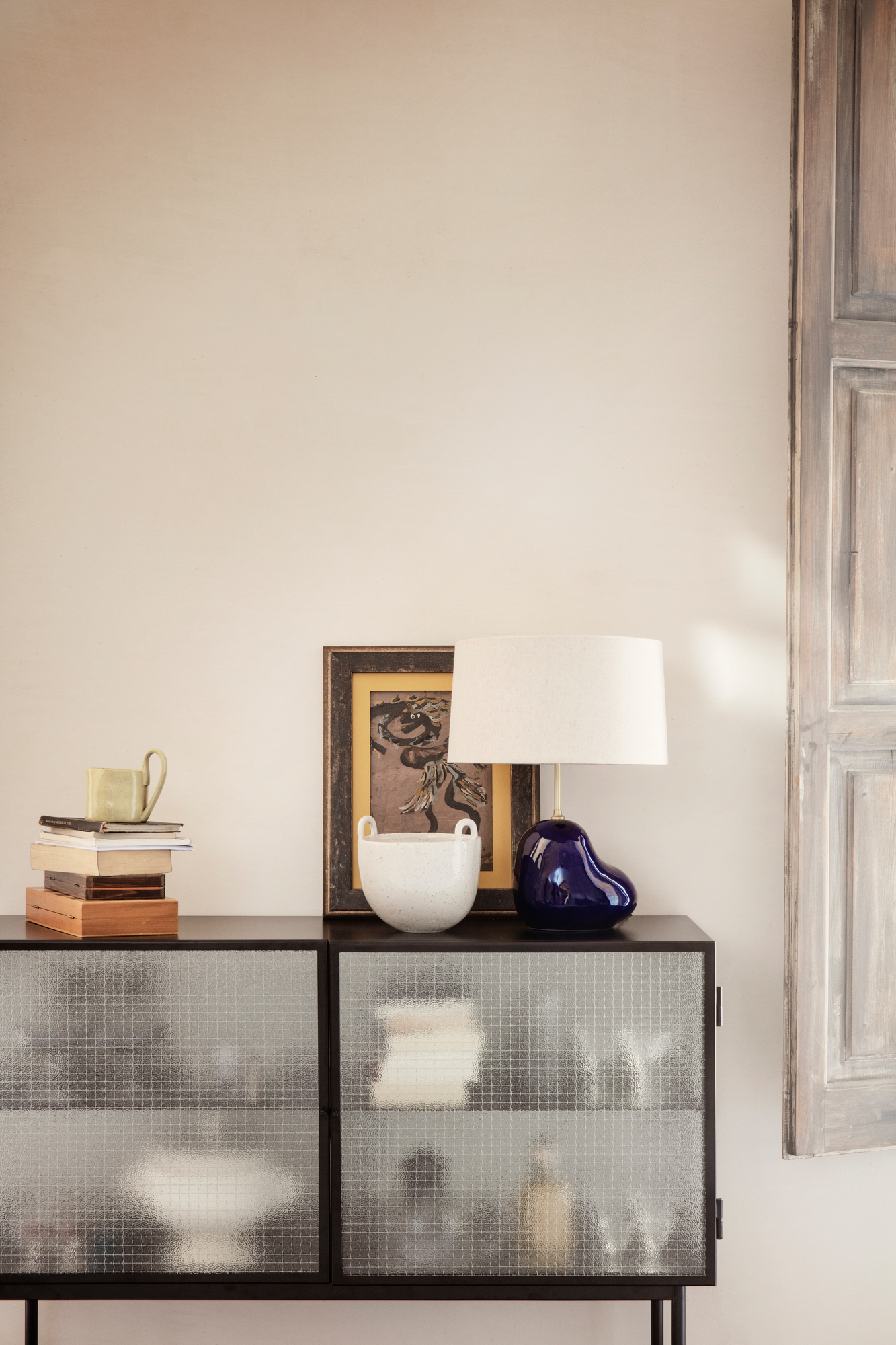 Schwarzes Haze Sideboard von Ferm Living mit strukturierten Glastüren und Deko-Objekten auf der Oberseite.