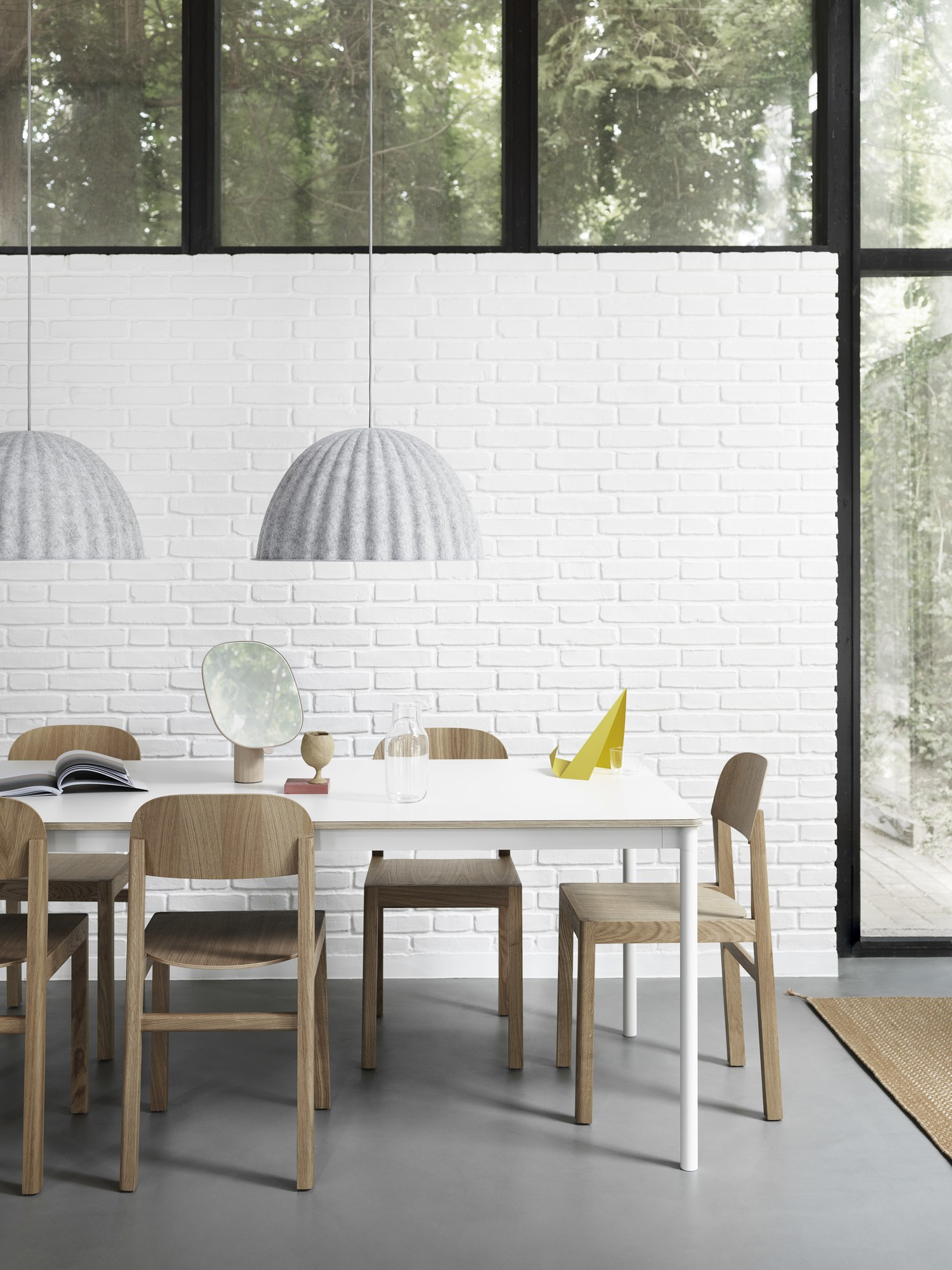 Esszimmer mit Esstisch, Holzstühlen und zwei grauen Under The Bell Pendelleuchten von Muuto.