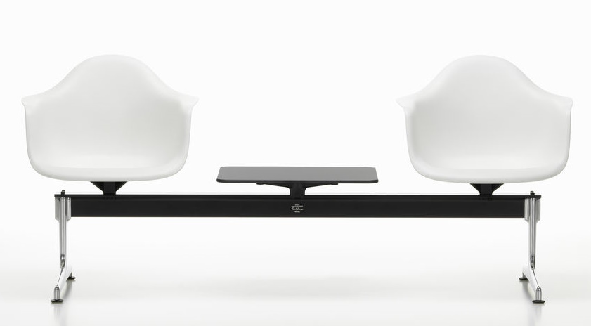 Zwei weiße Eames Plastic Armchairs auf schwarzer Traverse von Vitra mit kleinem Tisch.