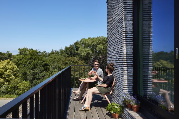Extremis Bistroo Stuhl und Tisch Outdoor-Set auf Balkon mit Paar, das Getränke genießt.