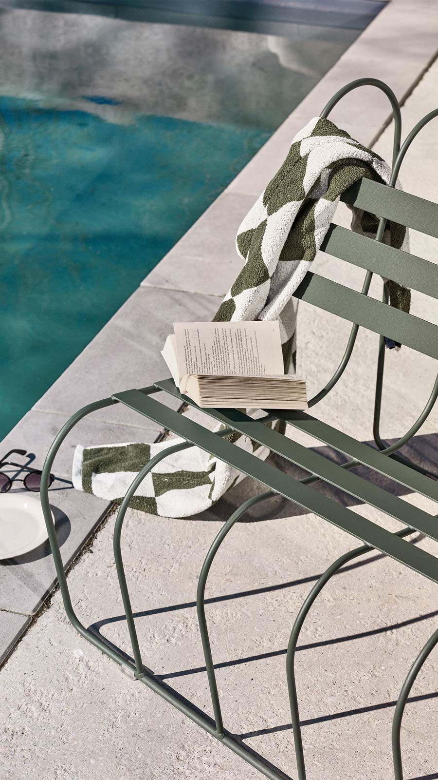 Gardener's Sofa von Design House Stockholm: Grüne Gartenbank am Pool mit Buch und Handtuch.