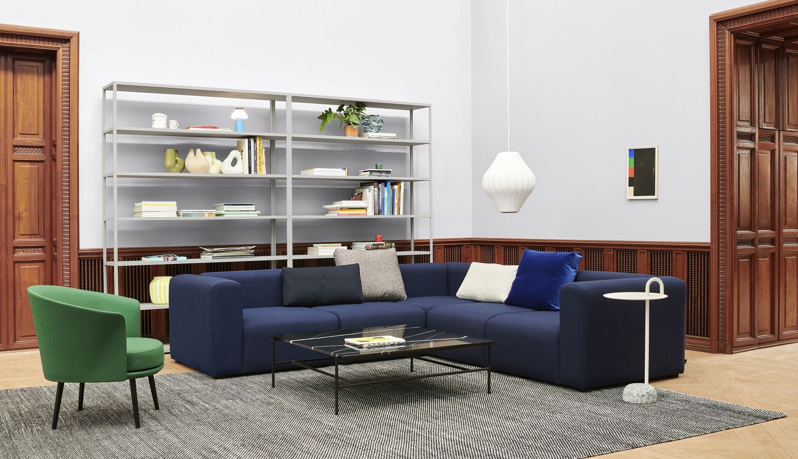 Heller Wohnraum mit blauem Ecksofa, Couchtisch, Bücherregal und Hay Bowler Beistelltisch mit Marmorfuß.