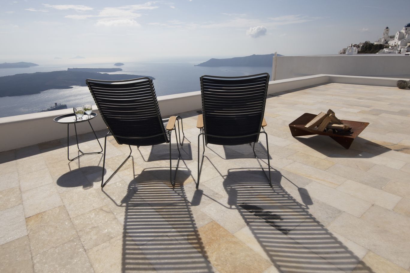 Zwei dunkelgraue Click Lounge Sessel von Houe Outdoor auf einer Terrasse mit Meerblick.