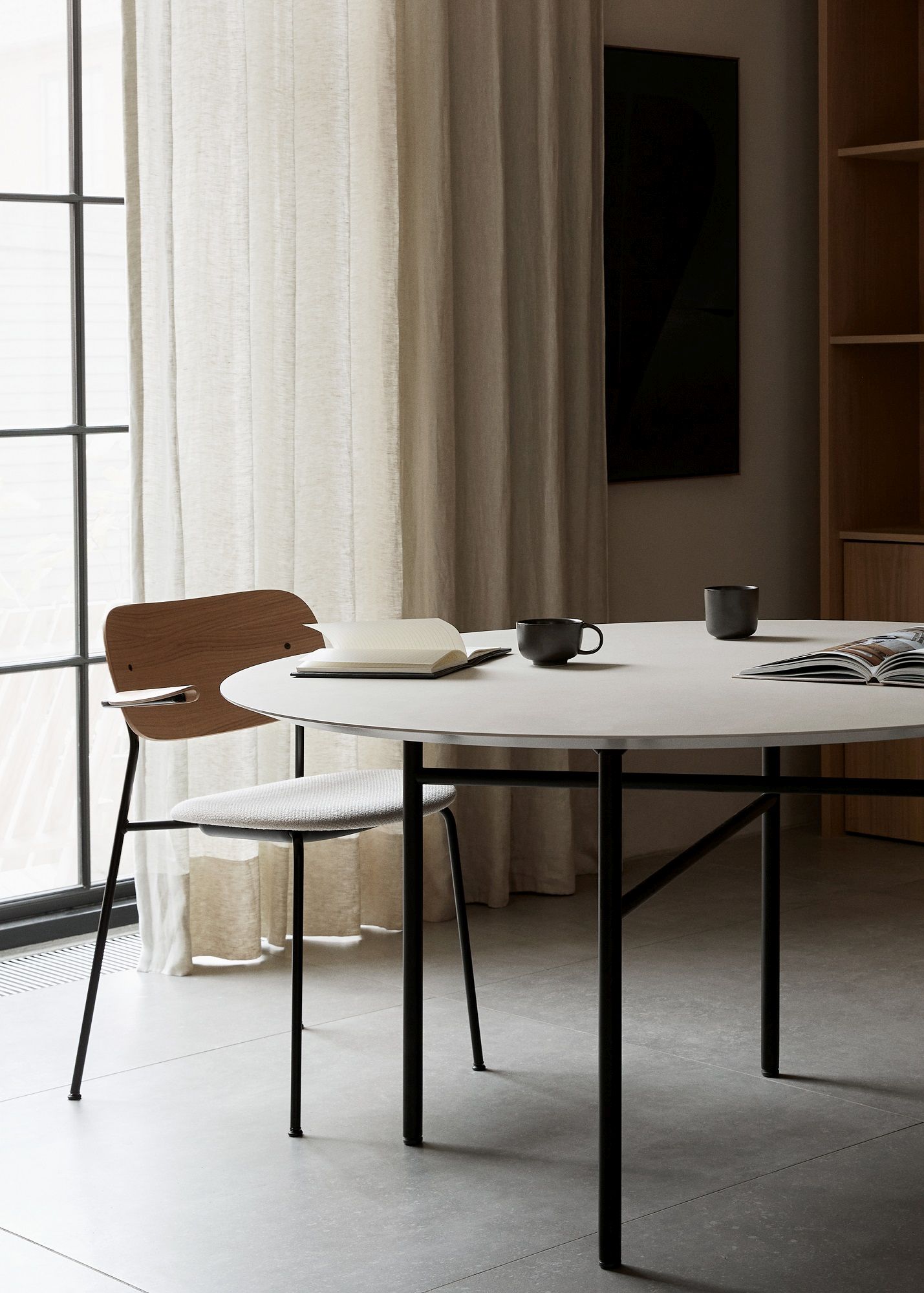Co Dining Chair Stuhl von Audo Copenhagen am Esstisch mit zwei Tassen und Notizbuch.