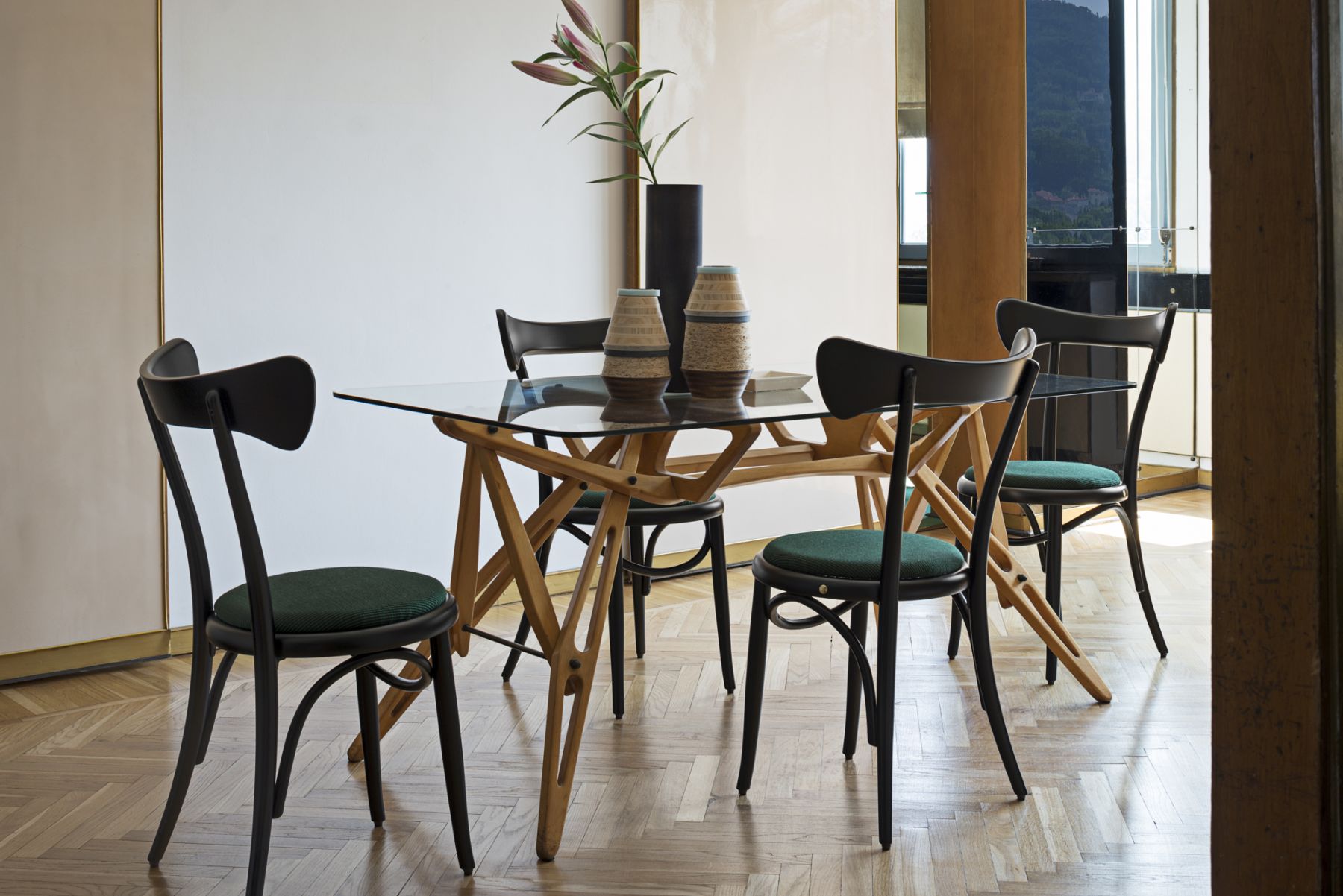 Caféstuhl im Wiener GTV Design, schwarzes Holz mit grüner Sitzfläche, am Esstisch.