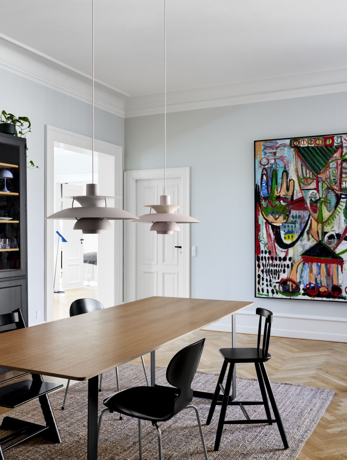 Zwei Louis Poulsen PH 5 Pendelleuchten in Rosa und Grau über einem Esstisch in modernem Interieur.
