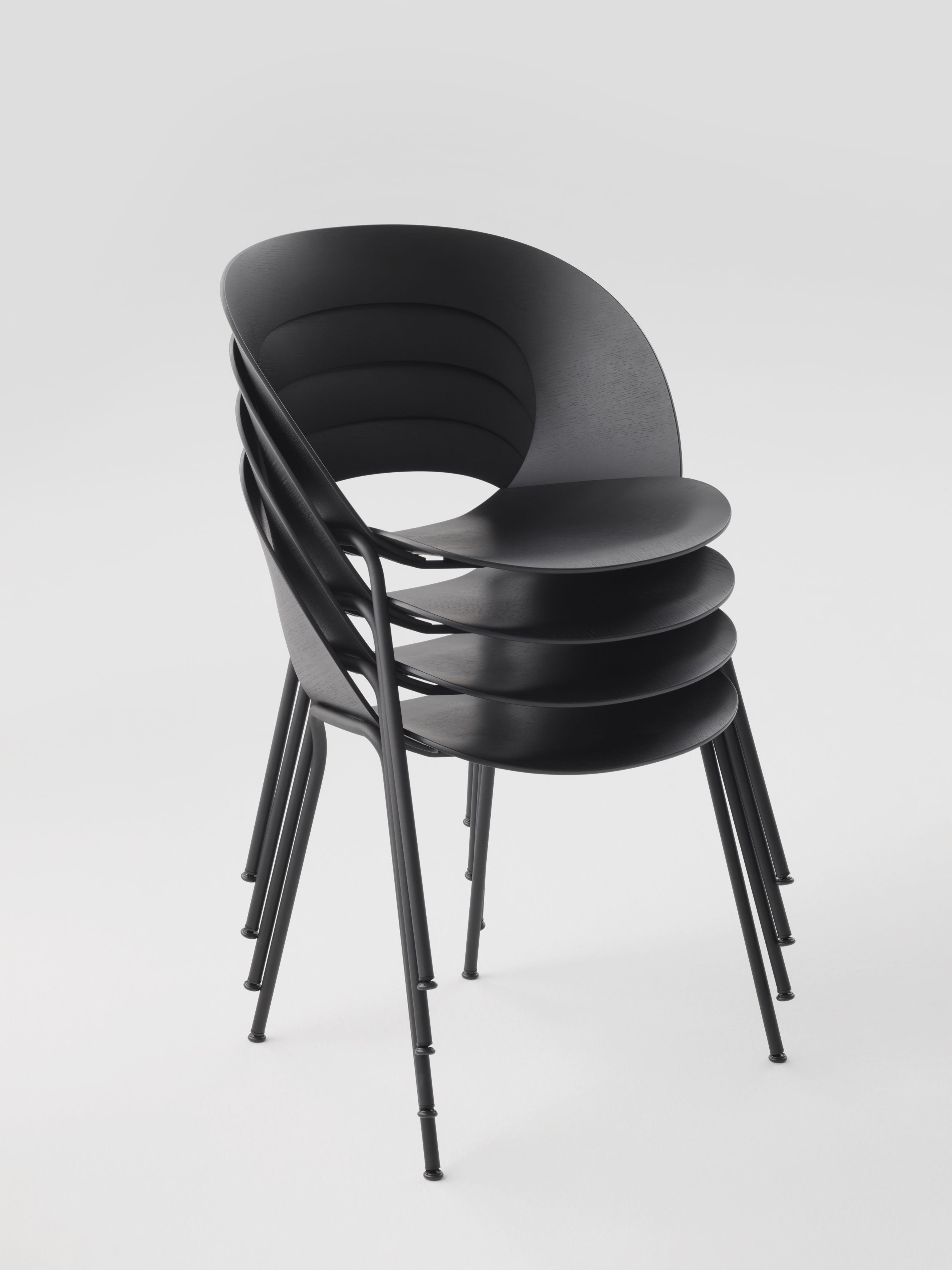 Stapel aus vier schwarzen Brunner Mudra Stühlen mit minimalistischem Design auf weißem Hintergrund.