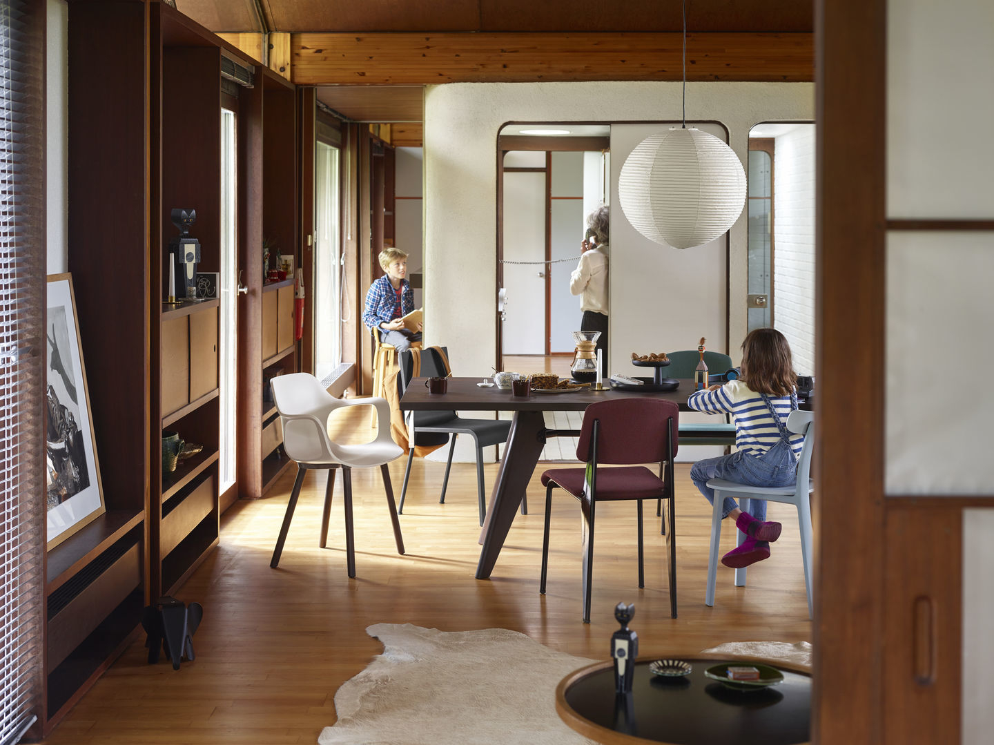 Esszimmer mit Akari Pendelleuchte von Vitra, die über einem dunklen Holztisch mit Stühlen hängt.