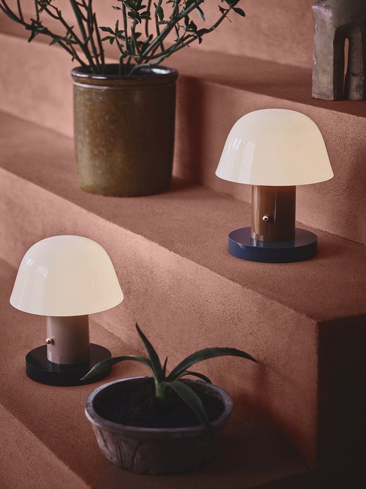 Zwei Setago Akkuleuchten von AndTradition auf einer Treppe, stimmungsvolle Tischleuchten im Pilzdesign.