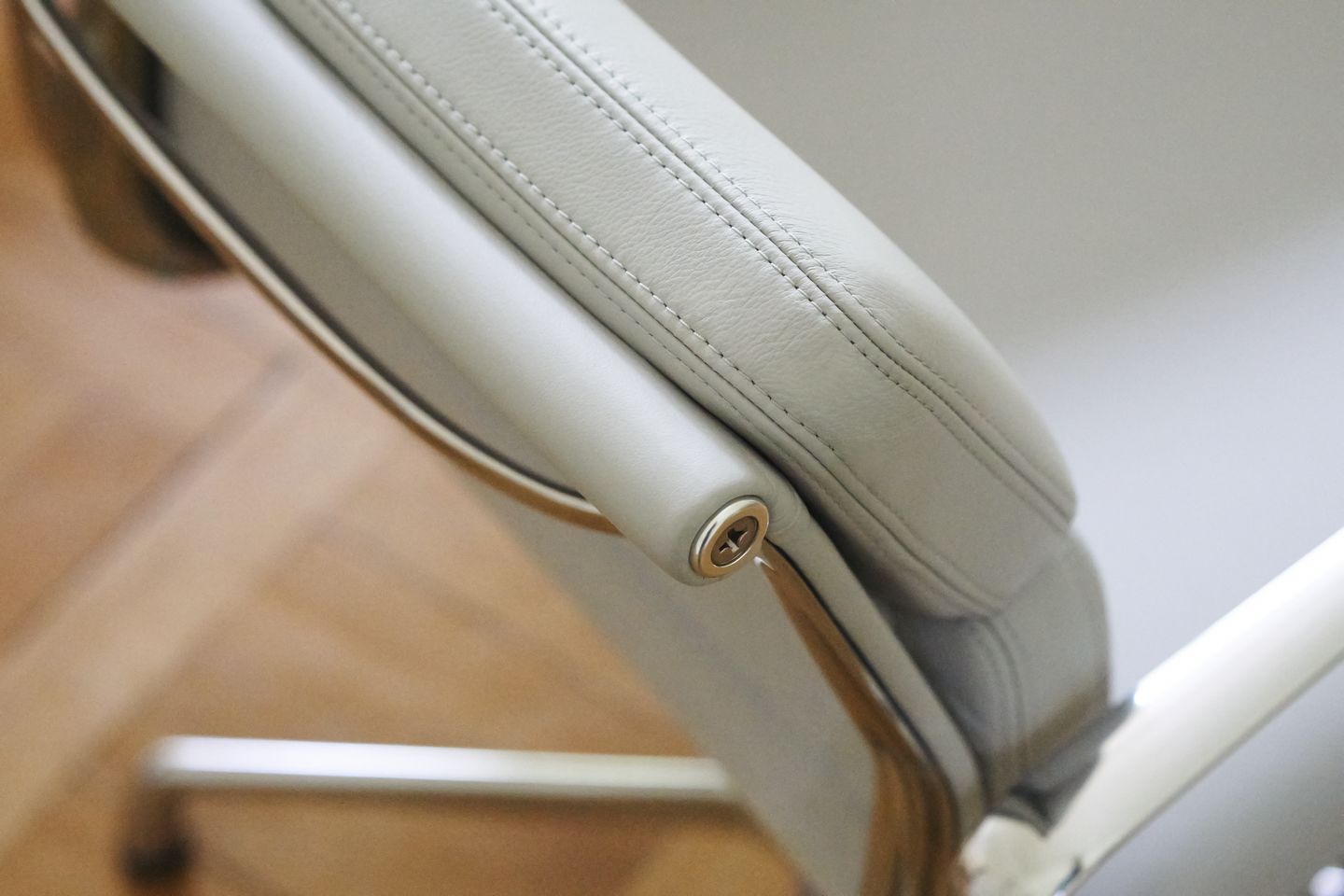 Detailaufnahme des Soft Pad Chair EA207 von Vitra, hellgraues Leder mit feinen Ziernähten und Armlehne.