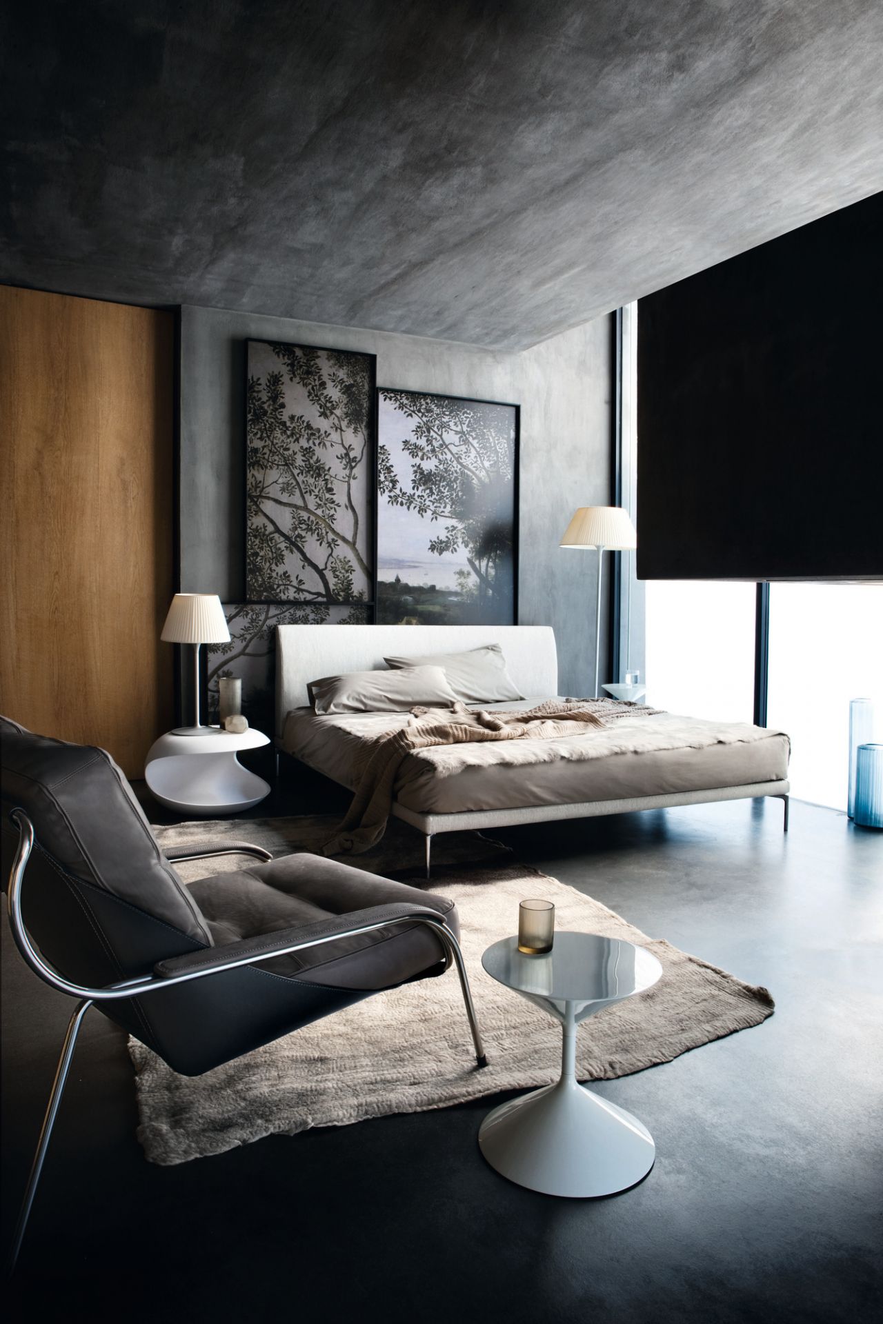 Modernes Schlafzimmer mit minimalistischem Bett, grauem Sessel und stilvoller Dekoration für ein elegantes Ambiente.