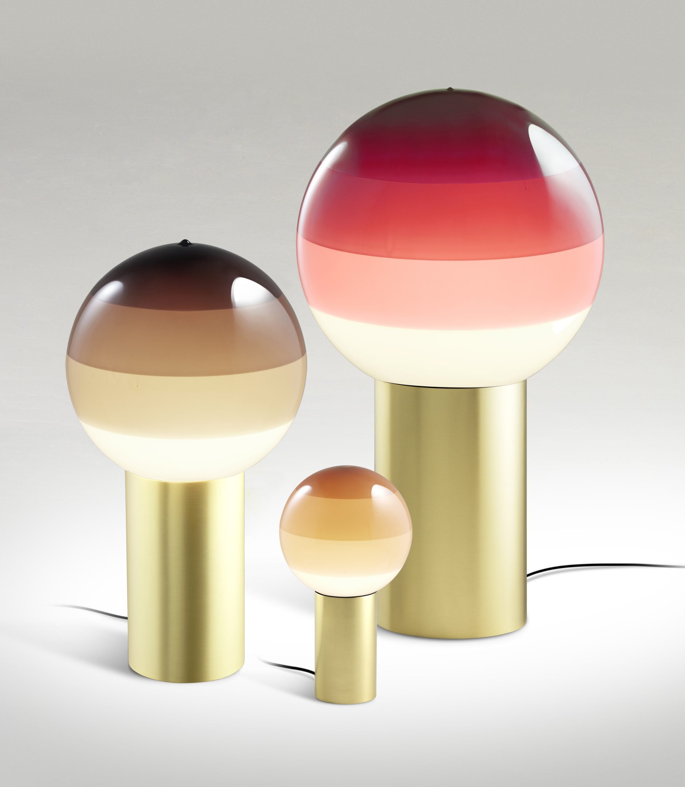 Drei Dipping Light Tischleuchten von Marset in verschiedenen Größen und Farbverläufen auf goldenem Sockel.