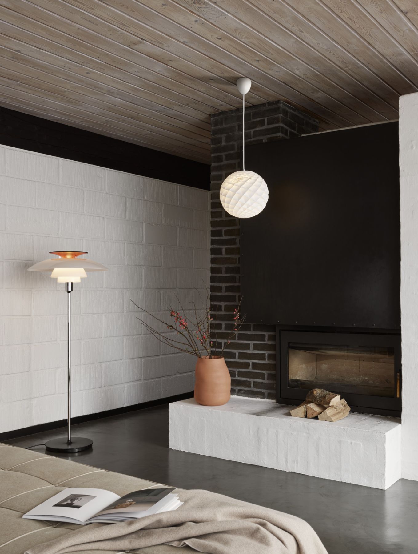 Moderne Wohnzimmer-Szene mit Louis Poulsen Stehleuchte, Pendelleuchte und Kamin für gemütliche Atmosphäre.