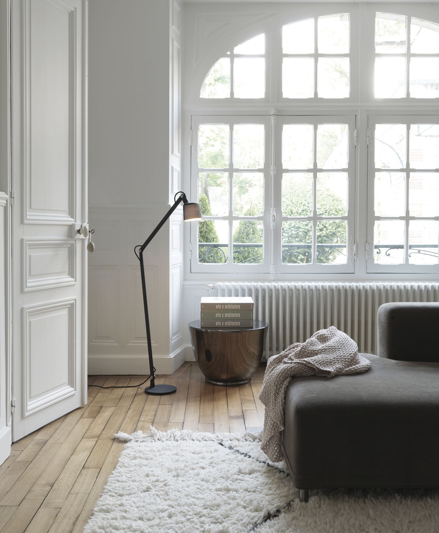 Schwarze Vipp Boden Leselampe im modernen Wohnzimmer mit Sofa, Teppich und großem Fenster für gemütliche Beleuchtung.