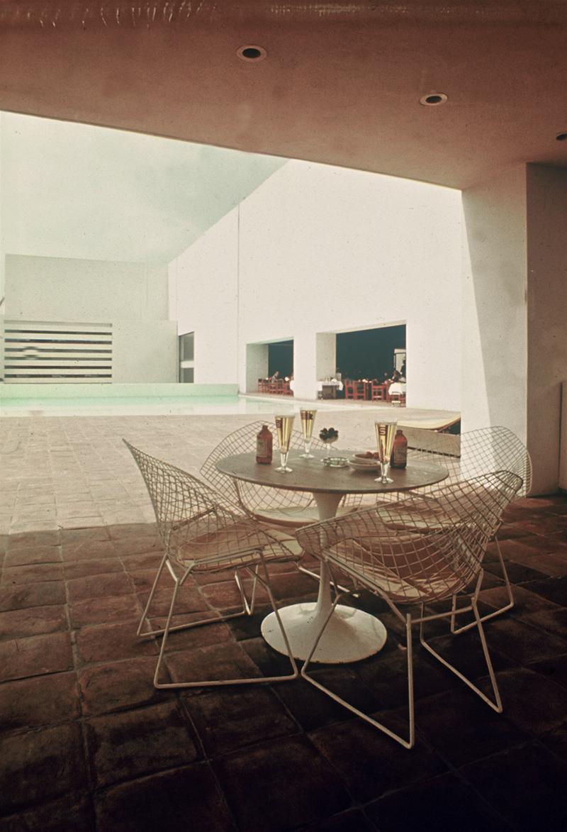 Saarinen Esstisch rund von Knoll International mit Drahtstühlen auf einer Terrasse mit Pool.