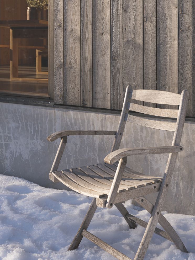 Selandia Armchair Sessel von Skagerak by Fritz Hansen aus Holz im Schnee vor Holzwand.