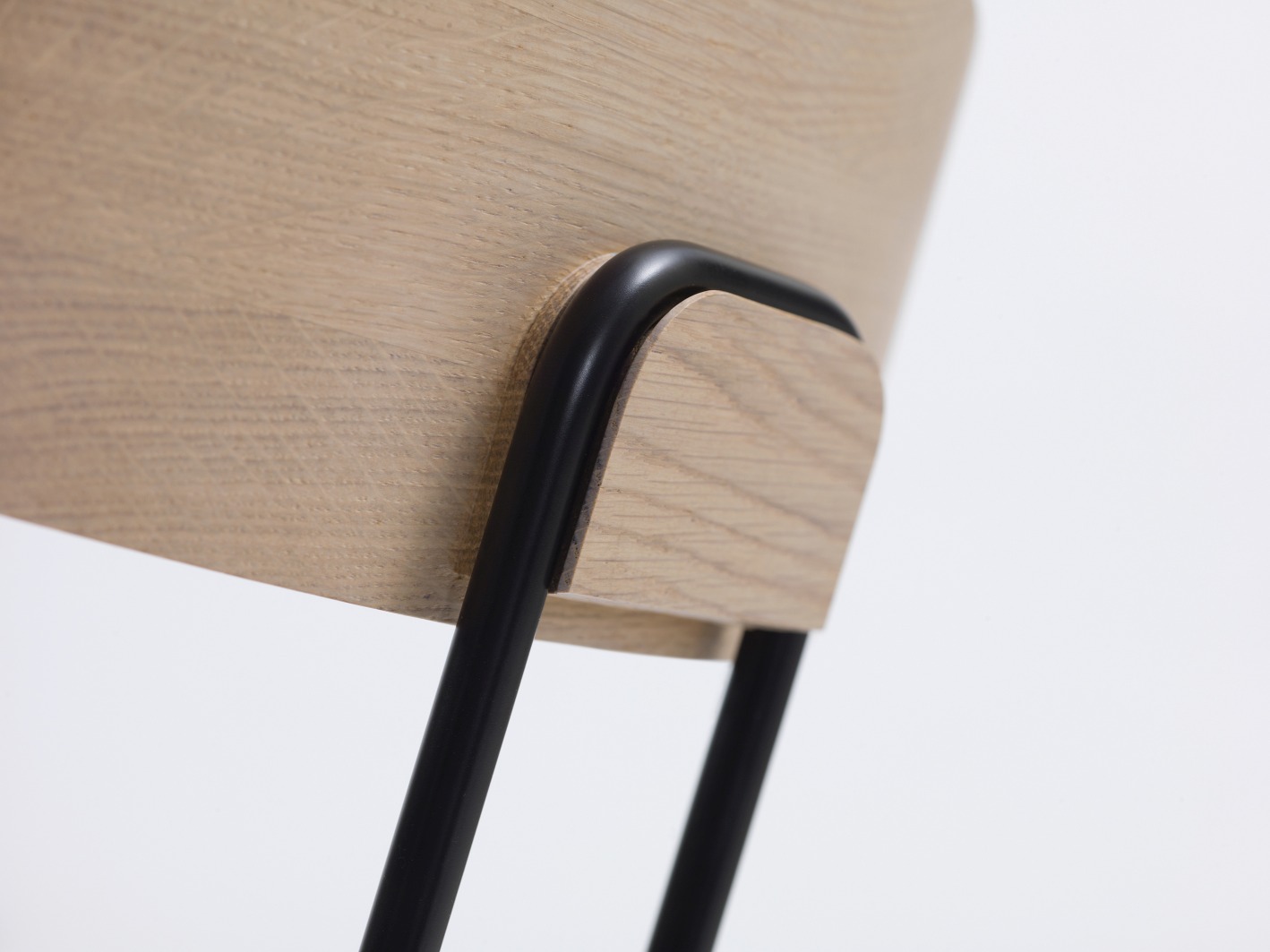 Detailaufnahme des Okito Chair Stuhls mit hellem Holz und schwarzen Metallbeinen für Esszimmer und Büro.