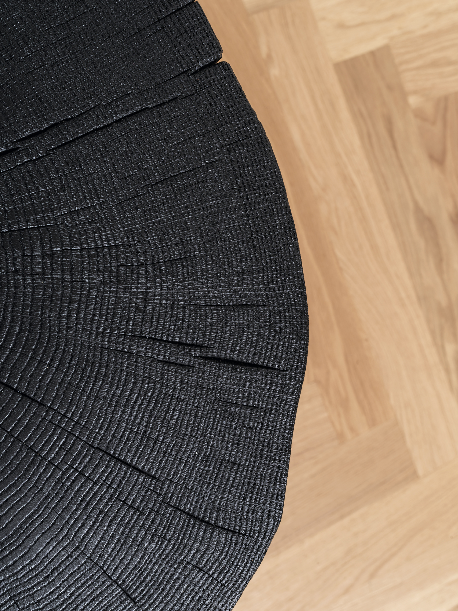 Detailaufnahme: Geköhlter Stomp Beistelltisch von Janua, H28. Schwarzer Holzhocker mit sichtbarer Maserung. Modernes Möbeldesign.
