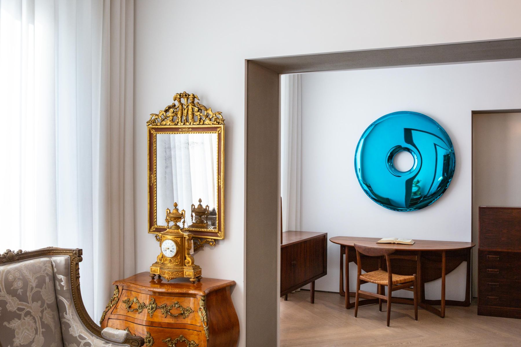 Elegantes Interieur mit antikem Spiegel, goldener Uhr und blauer Wandkunst für stilvolle Wohnräume.
