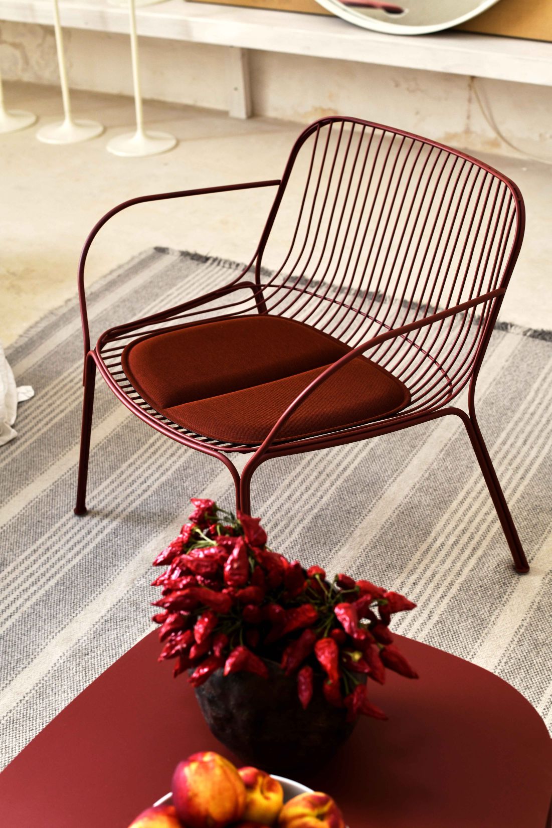 Nahaufnahme des roten Hiray Outdoor Sessels von Kartell mit Sitzkissen.