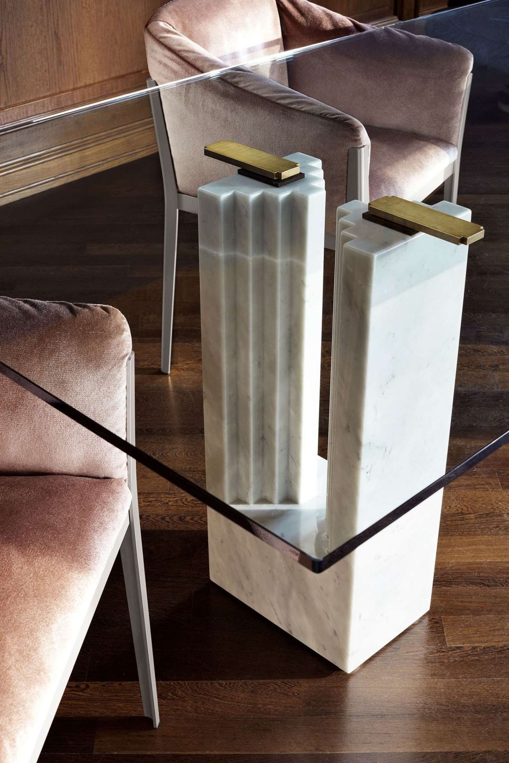 Detailaufnahme des Cassina Delfi Esstisches mit Marmor-Tischbeinen und Glasplatte, umgeben von eleganten Esszimmerstühlen.