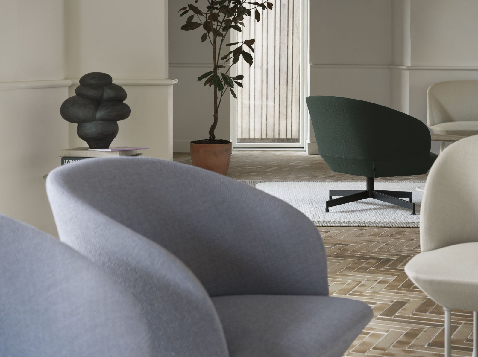 Nahaufnahme von grauen und grünen Oslo Lounge Sesseln von Muuto in einem stilvollen Wohnzimmer.